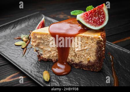 Käsekuchen auf dunklem Stein, Holzboden, mit Minze und Feigen Stockfoto