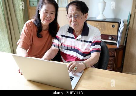 Das Paar Asiaten mit Laptop im Haus. Stockfoto