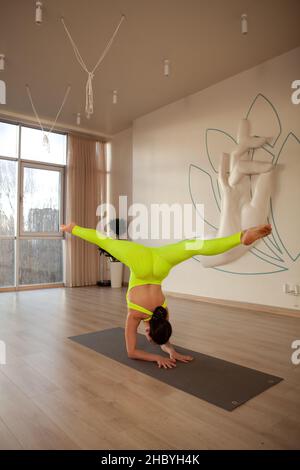 Vertikale Aufnahme einer weiblichen Turnerin, die Luftspalten macht und im Handstand steht Stockfoto