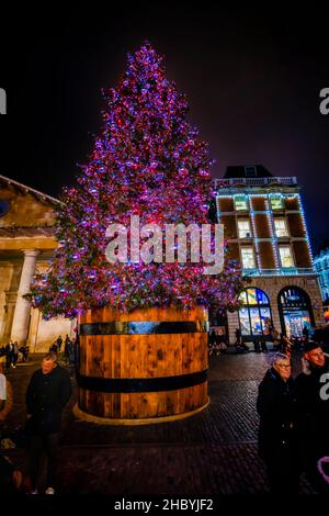Ein großer, beleuchteter Weihnachtsbaum mit roten und violetten Lichtern in Covent Garden, London WC2 in der Weihnachtszeit Stockfoto