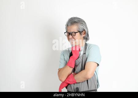 Die ältere asiatische Haushälterin, die auf weißem Hintergrund steht. Stockfoto