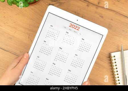 2022 Kalender auf Tablet-Computer-Bildschirm. Business Holztisch Desktop Hintergrund. Konzept der Planung von Termin und Treffen Stockfoto