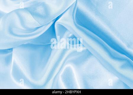Hellblaues Seidengewelltes Textilmuster als glatter strukturierter Hintergrund. Himmelfarbene Vorhänge aus weichem Satin-Stoff. Stockfoto