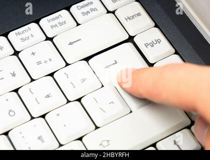 Mann, der die ENTER-Taste auf einer einfachen, weißen Laptop-Tastatur drückt, Nahaufnahme mit den Fingern, Details, Hand aus nächster Nähe. Bestätigung der Entscheidung, Senden einer Nachricht, a Stockfoto