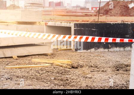 Warnband in Rot und Weiß in leuchtenden Farben zeigt gefährliche Baumaßnahmen, selektive Fokussierung Stockfoto