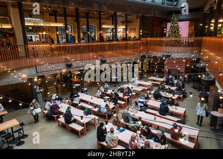 London, Großbritannien. 22. Dezember 2021. Ein paar Mittagspausen-Kunden in Seven Dials im Food Court. Hospitality-Unternehmen sehen sich in der Zeit, in der sie normalerweise am meisten frequentierten Zeit des Jahres sind, mit reduzierten Einnahmen konfrontiert, da die Kunden aufgrund der Omicron-Variante Buchungen stornieren. Rishi Sunak, Schatzkanzler, hat Pläne für einen £1bn-Fonds angekündigt, um Unternehmen zu helfen, die von dem Anstieg der Covid-Fälle betroffen sind, einschließlich des Freizeit- und Gastgewerbes. Kredit: Stephen Chung / Alamy Live Nachrichten Stockfoto