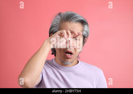 Das Porträt eines älteren asiatischen Mannes ohne retuschierte Haut auf dem rosa Hintergrund. Stockfoto
