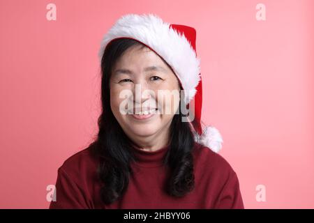 Das Porträt einer älteren asiatischen Frau ohne retuschierte Haut auf dem rosa Hintergrund. Stockfoto