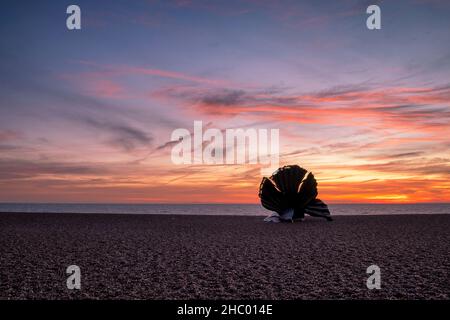 Sonnenaufgang über Maggi Hambling's Skulptur des Scallop am Kiesstrand in Aldeburgh, Großbritannien Stockfoto