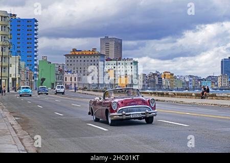 Oldtimer rot-amerikanischer Wagen, 1950s Buick, privates Taxi auf der Malecón / Avenida de Maceo, Avenue und Ufermauer entlang der Stadt Havanna auf der Insel Kuba Stockfoto