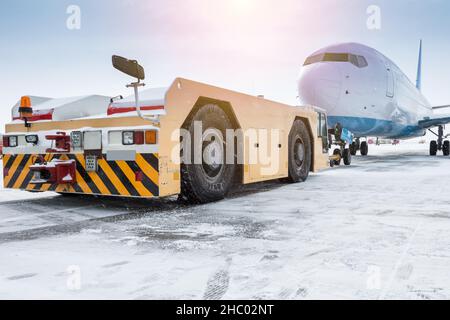 Der Schlepper schiebt das Passagierflugzeug im kalten Winter flughafenvorfeld Stockfoto