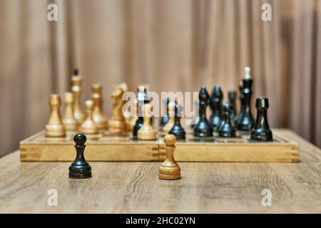 Alte Schachfiguren aus Holz auf Schachbrett.Weiße und schwarze Schachfiguren im Vordergrund. Beginn des Schachspiels. Stockfoto