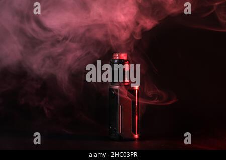 Elektronische Verdampfer mod, Zerstäuber steht in vape Rauch und Dampf durch rotes Licht beleuchtet. Stockfoto