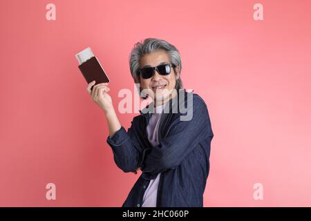 Der asiatische Mann, der auf dem rosa Hintergrund steht. Stockfoto