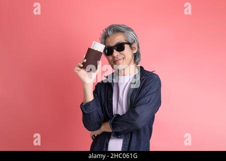 Der asiatische Mann, der auf dem rosa Hintergrund steht. Stockfoto