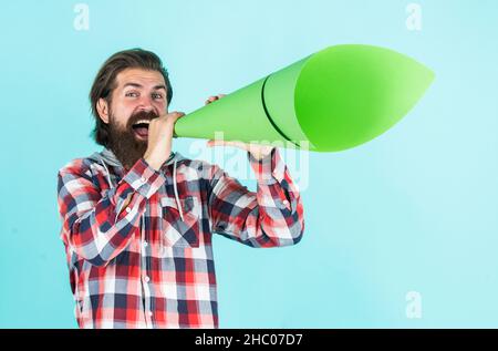 Reifer hübscher Mann im karierten Hemd sprechen in Papierlautsprecher, Werbung Stockfoto