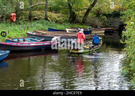 Pensioniertes Paar paddelt auf einem Klinkerboot in einem kleinen Seeufer im Killarney National Park, County Kerry, Irland, Europa Stockfoto