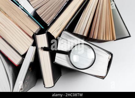 Lupe über verschiedenen Büchern. Konzept der Fokussierung auf Wissen und Studium. Stockfoto