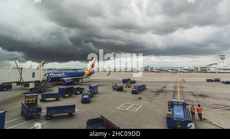 Dramatische Sturmwolken hängen über dem Tor am Flughafen, während das Flugzeug auf Asphalt sitzt Stockfoto