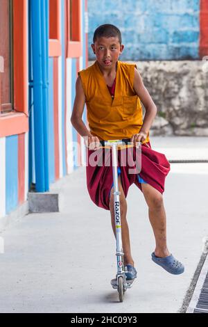 Ein junger buddhistischer Mönch, der auf einem Roller im Kloster Pema Tsal Sakya in der Nähe von Pokhara, Nepal, reitet. Stockfoto