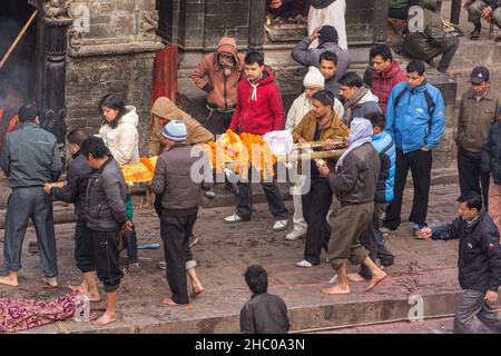 Trauernde tragen den Leichnam des Verstorbenen zur Einäscherungszeremonie im Pashumpatinath-Tempel, Kathmandu, Nepal. Stockfoto