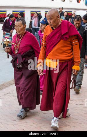 Ein buddhistischer Mönch und eine Nonne mit mala-Rosenkranz und Gebetsrad umkreisen die Boudhanath Stupa, Kathmandu, Nepal. Stockfoto