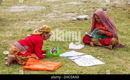 Zwei ältere nepalesische Frauen lernen in der Nähe des Himalaya-Vorgebirgsdorfes Dhampus, Nepal, lesen und schreiben. Stockfoto