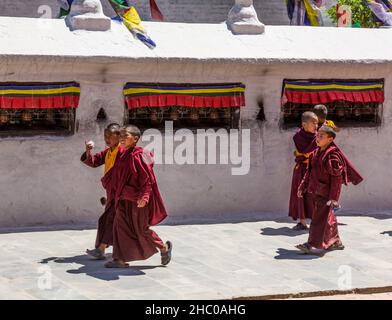 Junge buddhistische Novizen gehen an den Gebetsrädern der Boudhanath Stupa in Kathmandu, Nepal, vorbei. Stockfoto