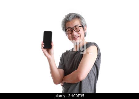 Der ältere asiatische Mann zeigt Gips auf seiner Schulter. Stockfoto