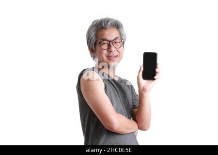 Der ältere asiatische Mann zeigt Gips auf seiner Schulter. Stockfoto