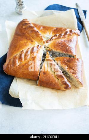 Frisch gebackene Fleischpastete auf einem Pergamentpapier auf Tischhintergrund. Pie mit Fleisch und Pilzen. Draufsicht. Rustikaler Stil Stockfoto