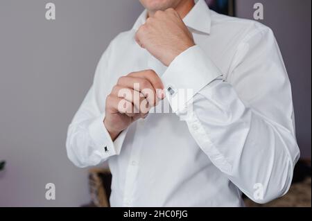 Mann, der ein Manschettenglied am Hemd befestigt. Der Bräutigam schließt Manschettenknöpfe am Hemd Stockfoto