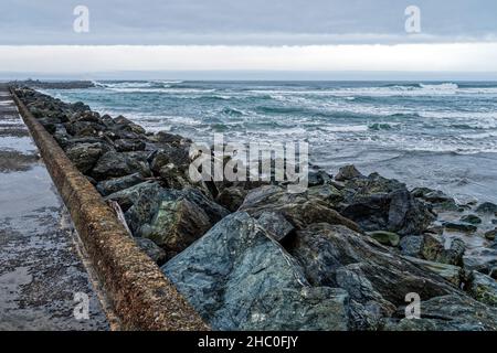 Felsen entlang der Anlegestelle, an der der Coquille River im Bullards Beach State Park, Oregon, USA, in den Pazifischen Ozean mündet Stockfoto