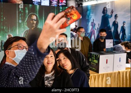 Hongkong, China. 22nd Dez 2021. Die Zuschauer lassen ihr Foto vor dem Filmbanner von Warner Bros. Picters für die Premiere des Films „Matrix Resurrections“ von Keanu Reeves in einem Kino in Hongkong machen. Kredit: SOPA Images Limited/Alamy Live Nachrichten Stockfoto