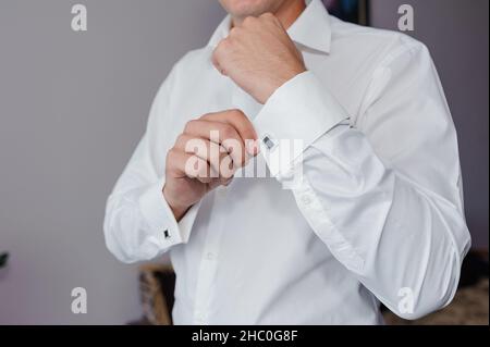 Mann, der ein Manschettenglied am Hemd befestigt. Der Bräutigam schließt Manschettenknöpfe am Hemd Stockfoto