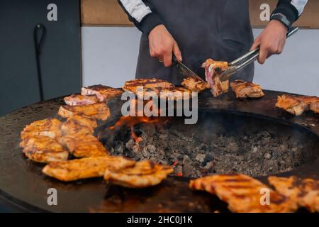 Koch hält Messer und schneidet frische, saftige Fleischsteaks auf dem Brazier Stockfoto