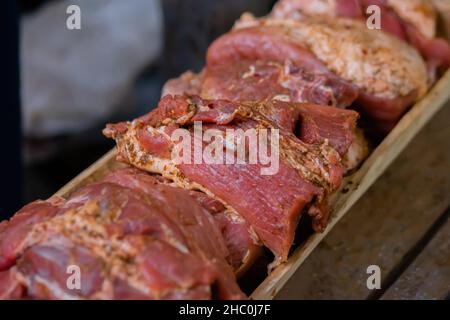 Frisch saftiges mariniertes Fleisch mit Gewürzen und Zwiebeln auf Holzbrett - Nahaufnahme Stockfoto