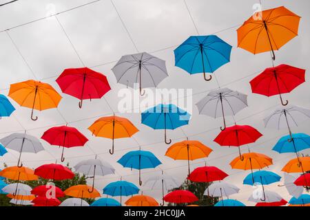 Bunte Regenschirme hängen beim Outdoor-Festival am bewölkten Himmel Stockfoto