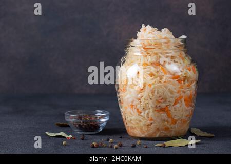 Hausgemachtes Sauerkraut mit Karotten im Glas auf grauem Hintergrund, fermentierte Nahrung Stockfoto