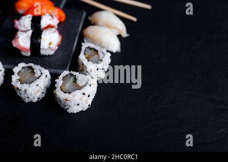 japanisches Sushi-Essen. Maki und Brötchen mit Thunfisch, Lachs, Garnelen, Krabben und Avocado. Draufsicht auf verschiedene Sushi-Sorten. Stockfoto