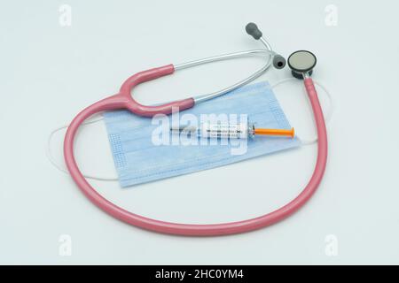 Covid 19 Spritze auf Maske mit Stethoskop. Gesundheitswesen und medizinisches Konzept . Omicron. Stockfoto