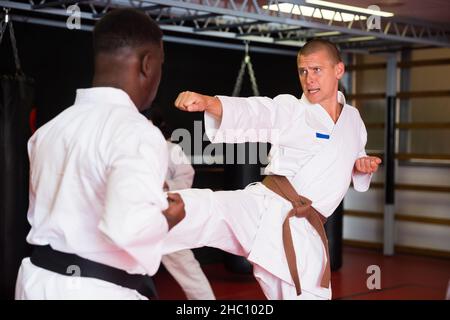 Männer, die beim Karate-Training im Fitnessstudio Sparring machen Stockfoto