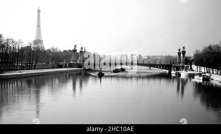 Blick nach Westen von Pont de la Concorde über die seine in Richtung Pont Alexandre III und darüber hinaus. Ein Schleppkahn nähert sich, während mindestens fünf Lastkähne dahinter gezogen werden. Der Eiffelturm ist im linken Hintergrund und der Palais de Chaillot ist hinten in der Mitte. Stockfoto