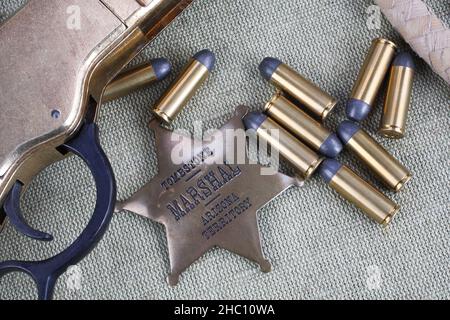 Altes Westgewehr, Munitions- und Sheriff-Abzeichen auf Leinwandhintergrund Stockfoto