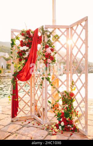 Auf dem gepflasterten Pier steht eine hölzerne, faltbare Hochzeitsleinwand Stockfoto