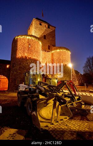 Ahrweiler, Deutschland. 21st Dez 2021. Baumaschinen stehen vor dem weihnachtlich beleuchteten Ahr-Tor in Ahrweiler. Zu Weihnachten 2021 sind zahlreiche Familien im überfluteten Ahrtal auf Notunterkünfte angewiesen. Bei den extremen Überschwemmungen Mitte Juli kamen hier 134 Menschen ums Leben, mehr als 750 wurden verletzt und Tausende von Häusern wurden beschädigt oder zerstört. (To dpa: Feiertage für Flutopfer im Ahrtal - Weihnachten am Wasser). Quelle: Thomas Frey/dpa/Alamy Live News Stockfoto