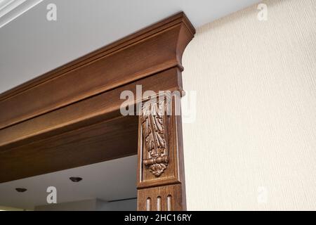 Dekorierter Holzeingang mit geschnitzten Möbelhalterungen und geriffelten Paneele in klassischem Stil in hellem, geräumigen Zimmer in Nahaufnahme Stockfoto