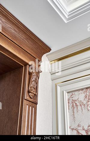 Verzierte hölzerne Tür mit geschnitzten Möbelhalterungen und geriffelten Paneele und Vintage Wandpaneel mit goldenen Zierleisten in klassischem Stil Nahaufnahme Stockfoto