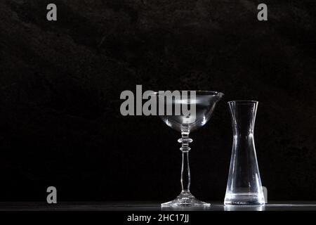 Leere Cocktailgläser und -Behälter vor einem Hintergrund aus dunklen Marmorfliesen Stockfoto