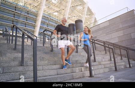 Reifes Paar, Mann und Frau in Sportkleidung machen zusammen eine Trainingseinheit und trainieren auf der Treppe im Freien Stockfoto